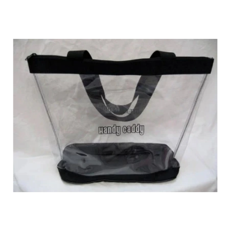 A clear plastic beach tote bag with black handles and a black base, photographed against a white fabric background. The text 'handy caddy' is printed on the front.